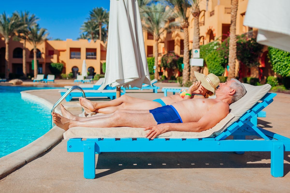Senior couple relaxing by swimming pool. People enjoying vacation in Egypt. All inclusive